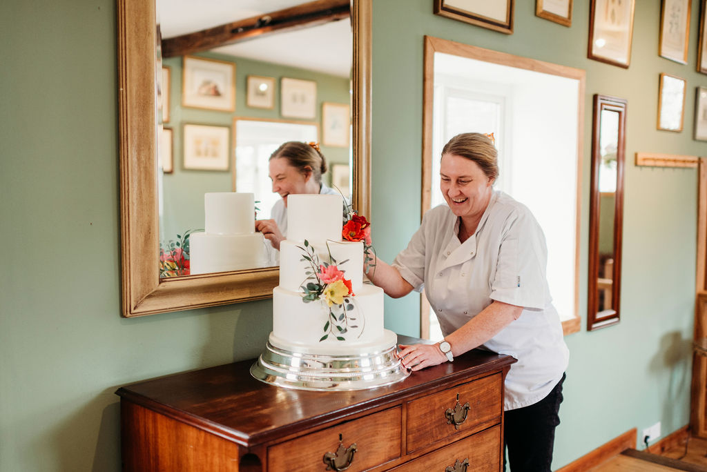 Photo Credit: Srah J Scott Photography Louise putting the finishing touches to a bright summery cake with sugar poppies.