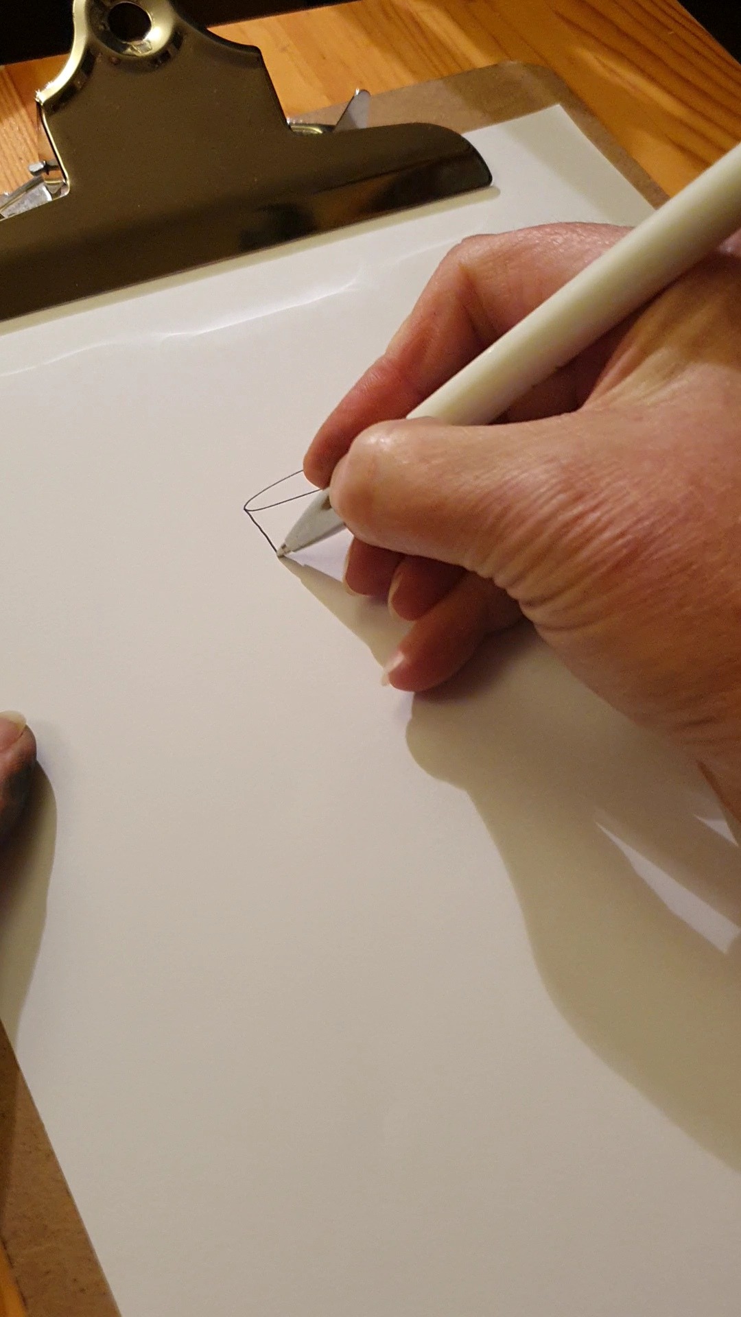 Starting to draw a custom cake design on a piece of paper held in a clipboard